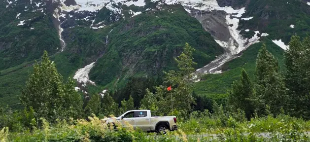 Turning Point Surveys truck in grass with mountain and clouds in the background